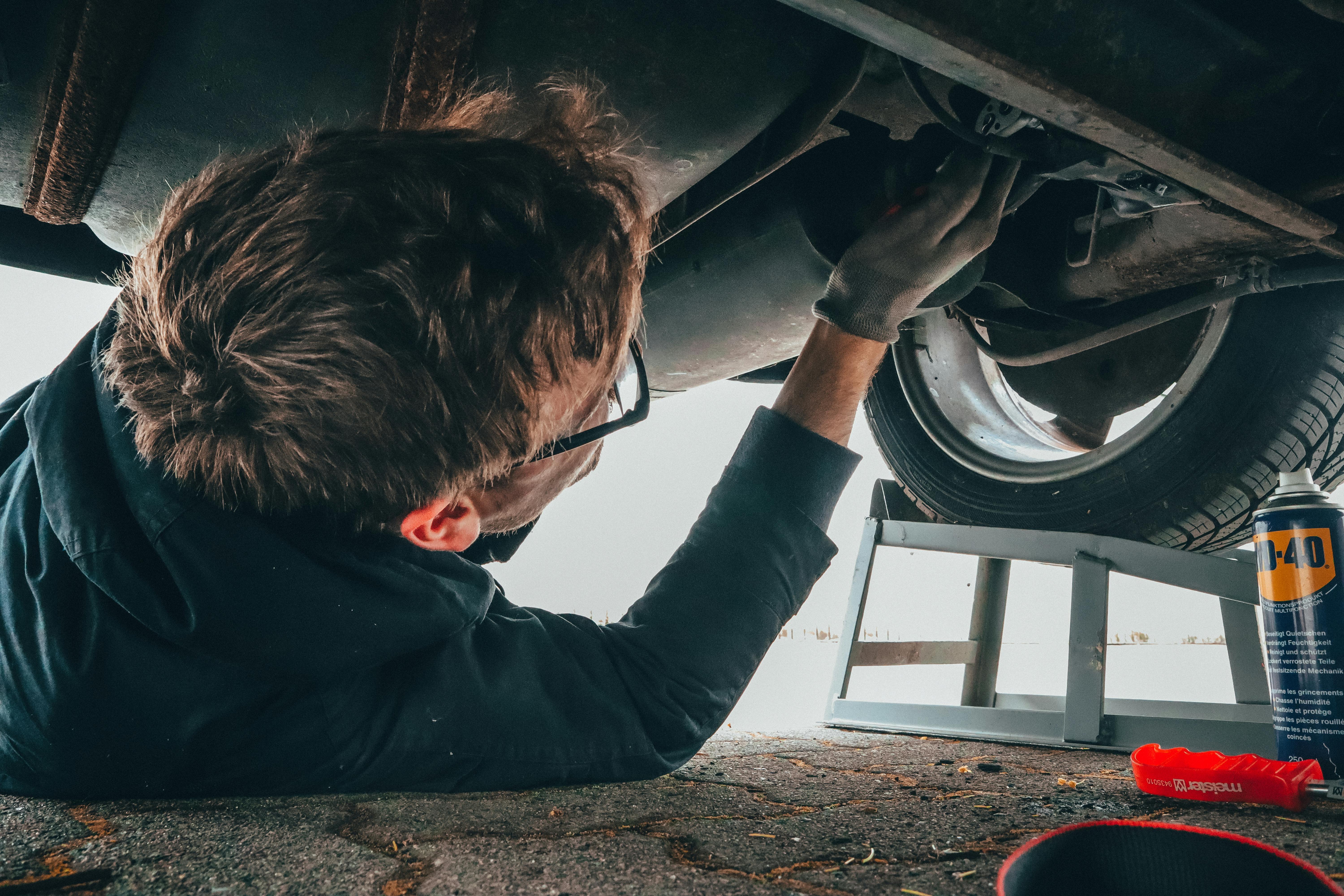 Mechanic inspecting underside of car