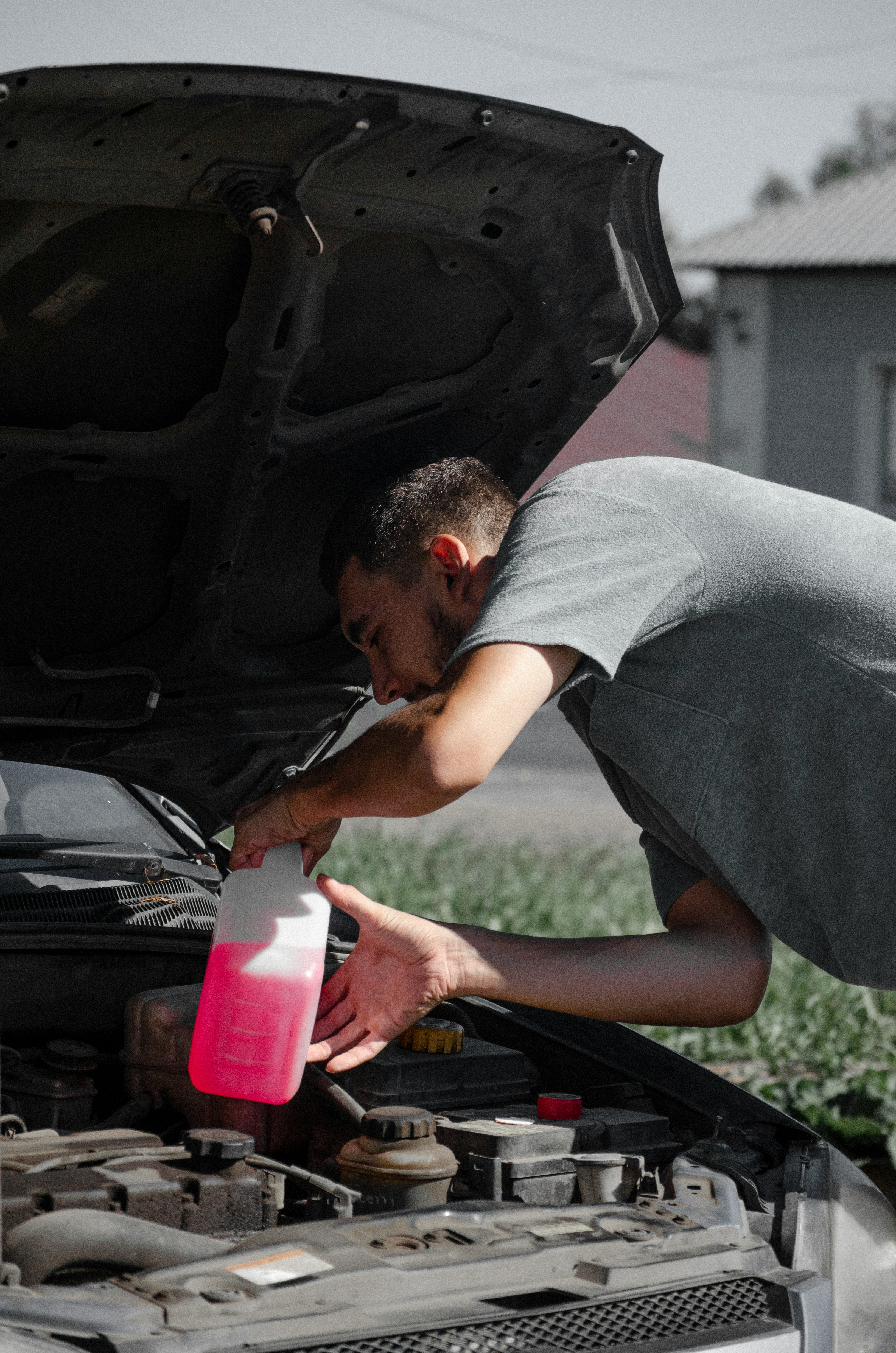 A man adding coolant to a cars engine